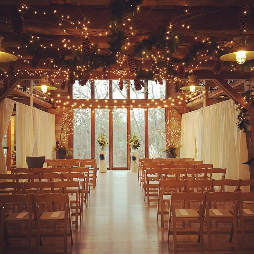 Indoor ceremony setup at Pat's Barn with chairs, aisle, lights, pinecones and other greenery.�