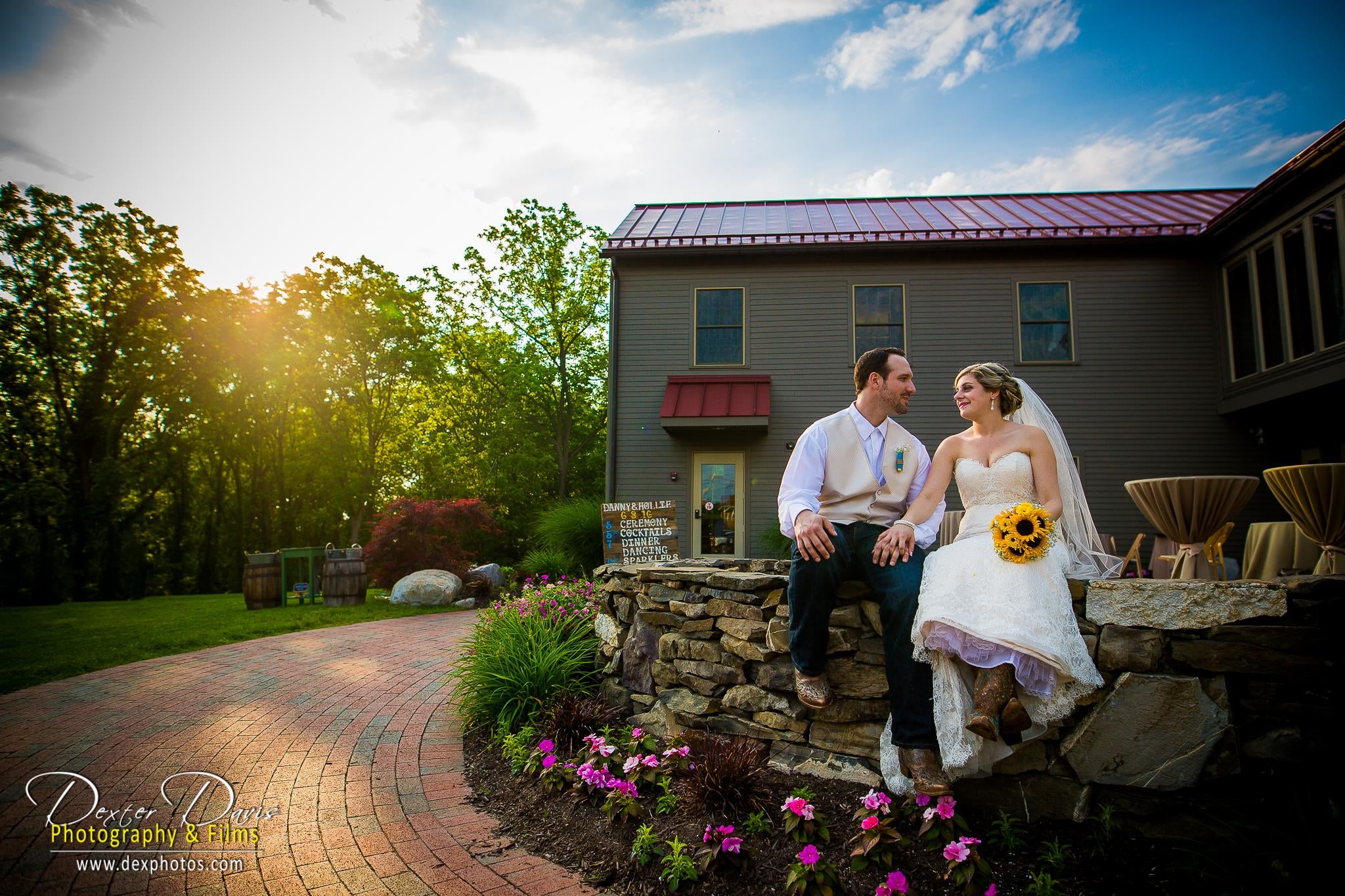 Bride and groom sitting together on a rock wall outside Pat's Barn.�