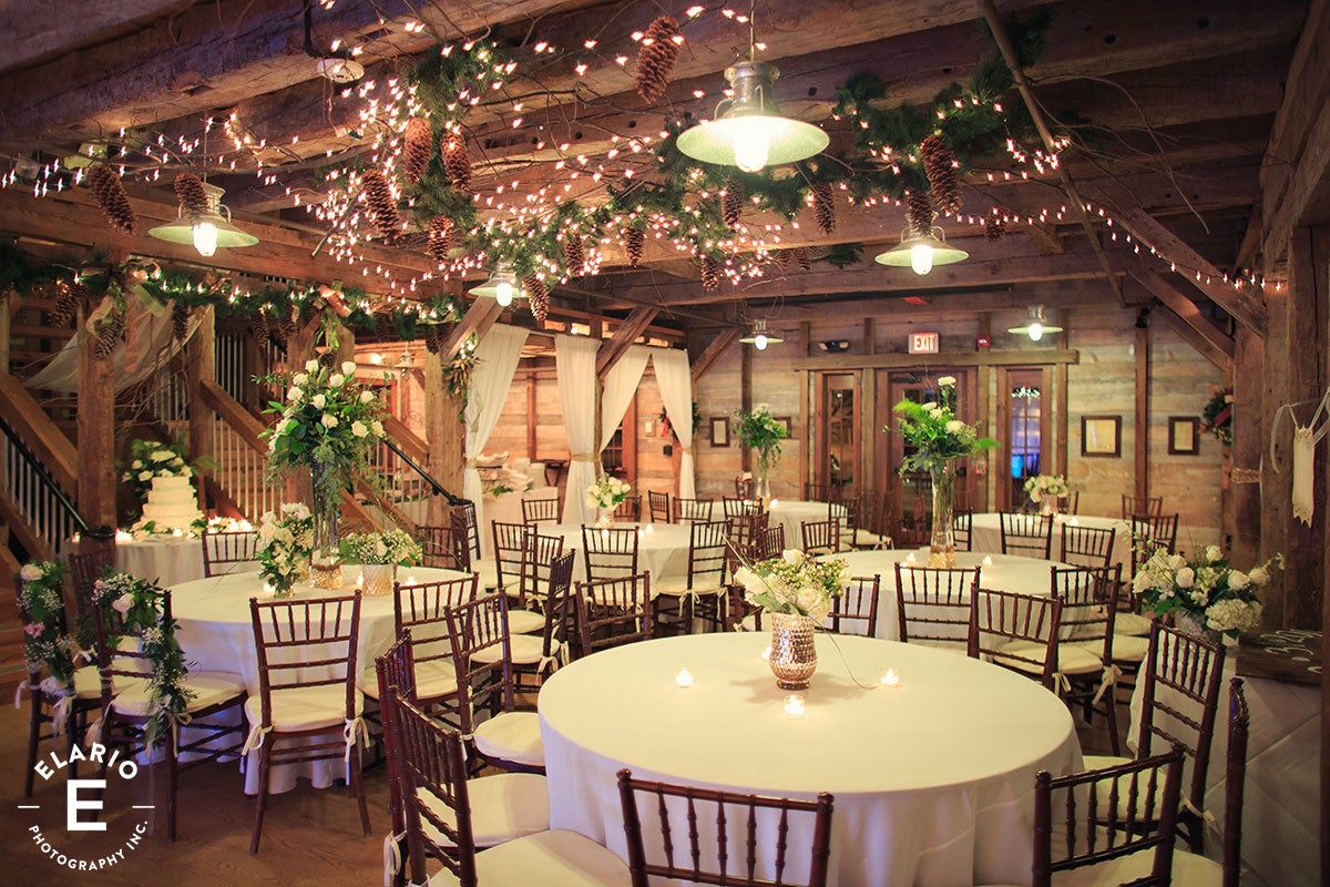 Reception area inside of Pat's Barn set up with decorated tables, lights, pinecones and florals.�